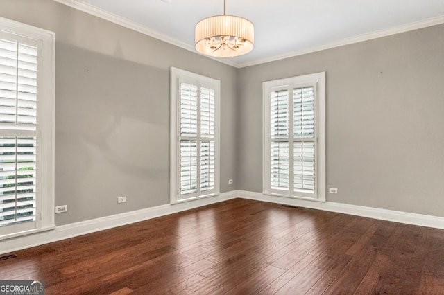 empty room with dark hardwood / wood-style floors, an inviting chandelier, and ornamental molding