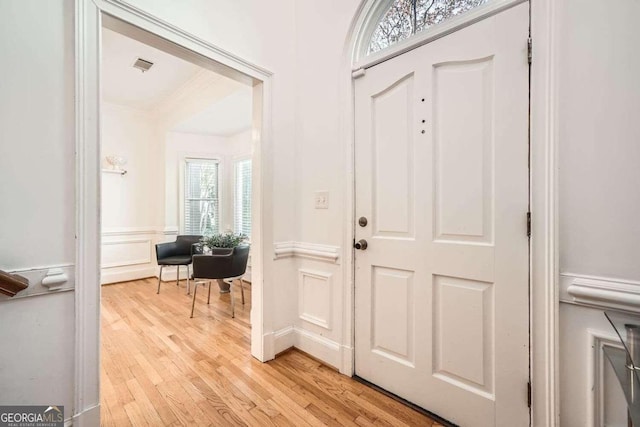 entrance foyer with ornamental molding and light hardwood / wood-style flooring