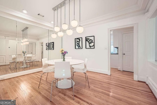 dining space with light hardwood / wood-style floors and ornamental molding