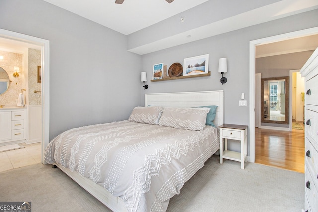 bedroom featuring ceiling fan, light hardwood / wood-style floors, and connected bathroom