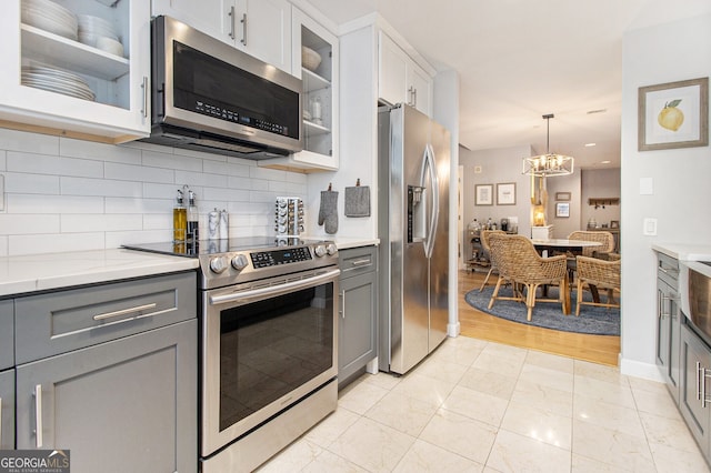 kitchen featuring white cabinets, gray cabinetry, light wood-type flooring, and stainless steel appliances