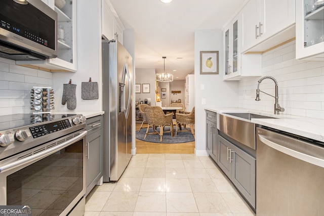 kitchen with white cabinets, light hardwood / wood-style floors, stainless steel appliances, and pendant lighting