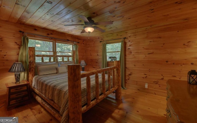 bedroom featuring light wood-type flooring, wooden walls, and multiple windows