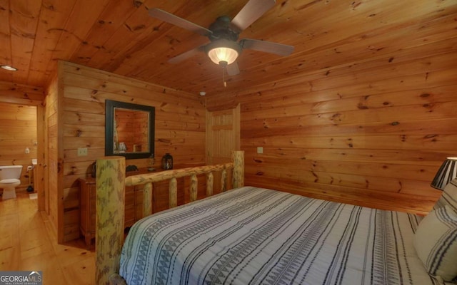 bedroom featuring ensuite bathroom, wood walls, and light wood-type flooring