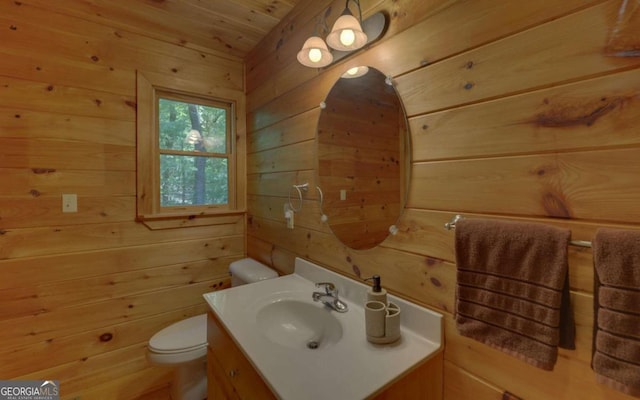 bathroom with vanity, toilet, and wooden walls