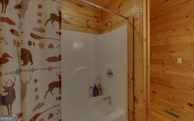 bathroom with shower / tub combo with curtain and wood walls