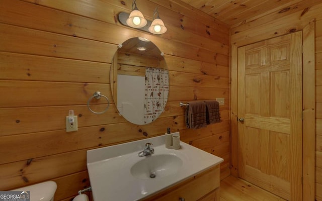 bathroom featuring curtained shower, wooden ceiling, wood walls, toilet, and vanity