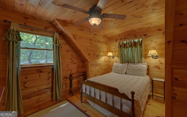 bedroom with light hardwood / wood-style floors, vaulted ceiling, ceiling fan, and wood walls