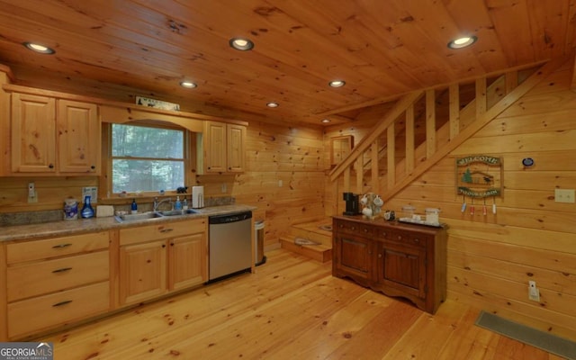 kitchen with light brown cabinets, light hardwood / wood-style floors, stainless steel dishwasher, and wooden walls