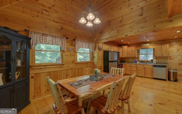 dining room featuring wood walls, sink, light hardwood / wood-style floors, and a notable chandelier