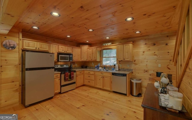 kitchen featuring sink, light brown cabinets, stainless steel appliances, light hardwood / wood-style flooring, and wooden walls