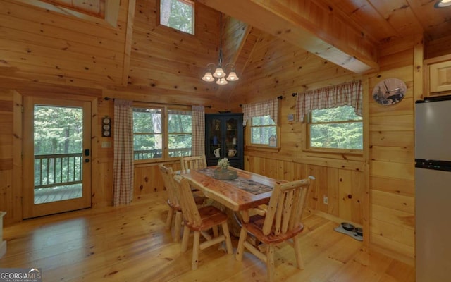 dining space featuring wooden walls, light hardwood / wood-style flooring, vaulted ceiling with beams, a notable chandelier, and wood ceiling