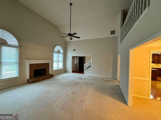 unfurnished living room featuring ceiling fan, light colored carpet, a fireplace, and high vaulted ceiling