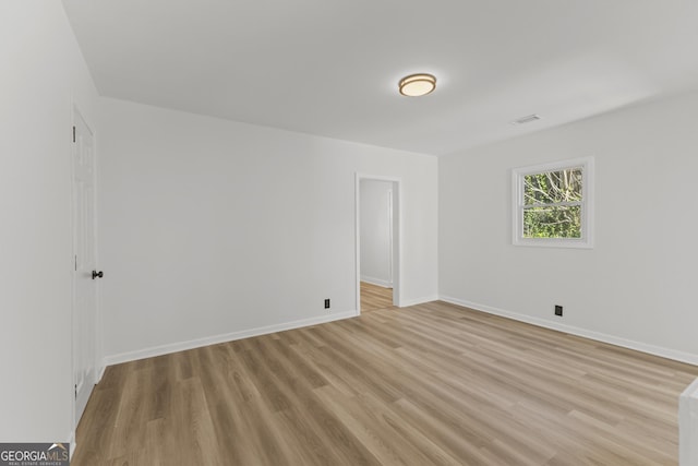 spare room featuring light wood-style floors, visible vents, and baseboards