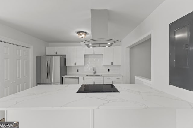 kitchen featuring black electric stovetop, freestanding refrigerator, a sink, island range hood, and electric panel