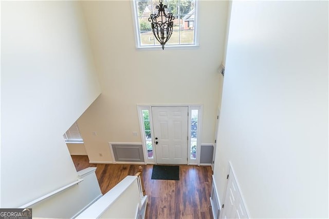 foyer with a towering ceiling, dark hardwood / wood-style floors, and a notable chandelier