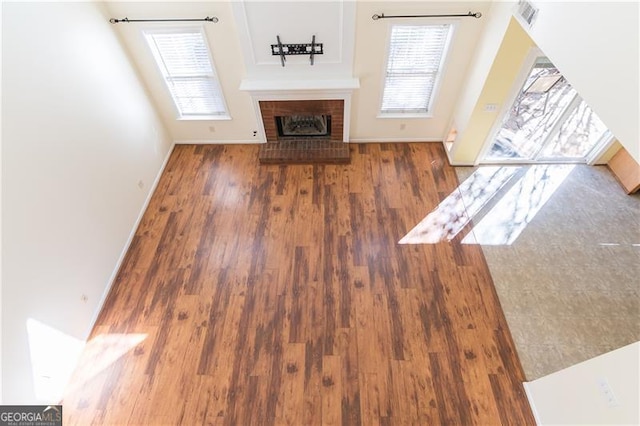 unfurnished living room featuring a brick fireplace and dark wood-type flooring