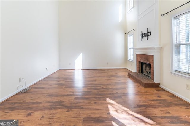 unfurnished living room featuring dark hardwood / wood-style floors and a brick fireplace