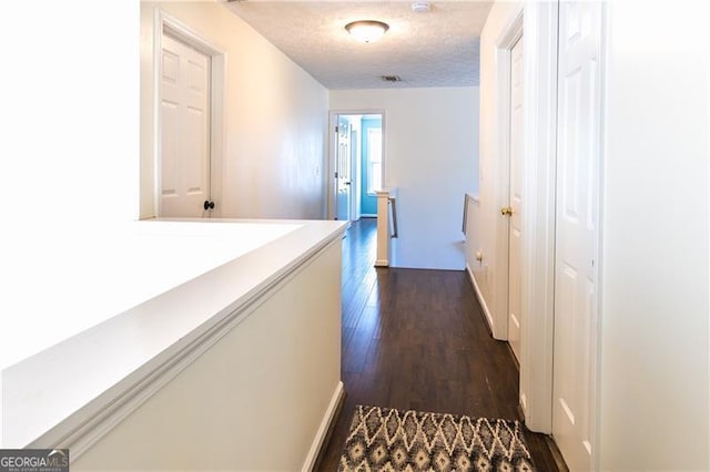 corridor featuring dark hardwood / wood-style floors and a textured ceiling