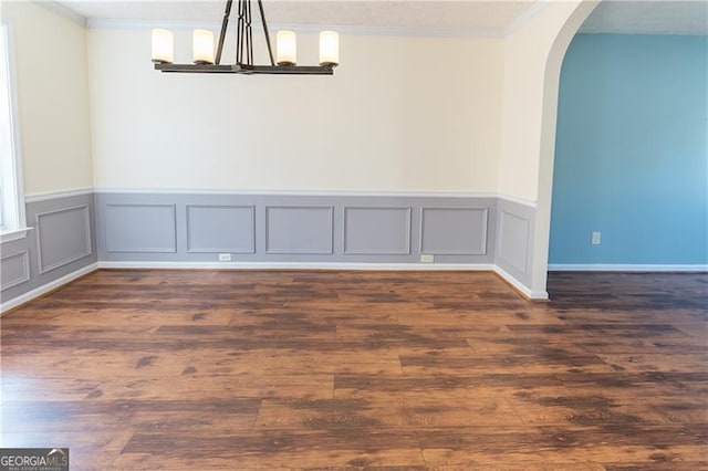 empty room featuring a chandelier, dark hardwood / wood-style flooring, and crown molding