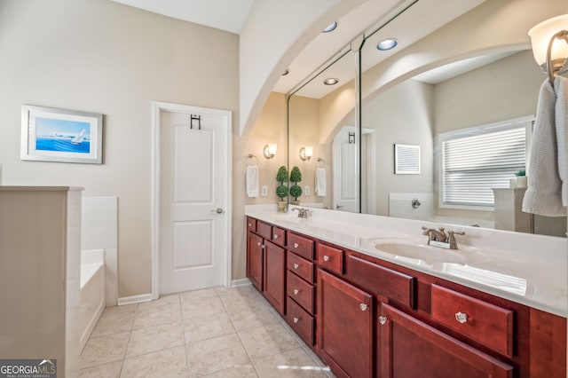 bathroom with tile patterned floors, a tub, and vanity