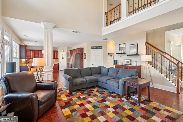 living room featuring dark hardwood / wood-style floors, ornate columns, and a high ceiling