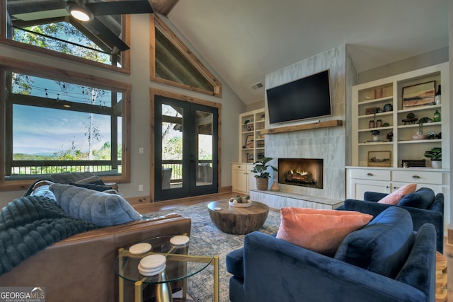 living room with a tiled fireplace, french doors, wood-type flooring, and built in features