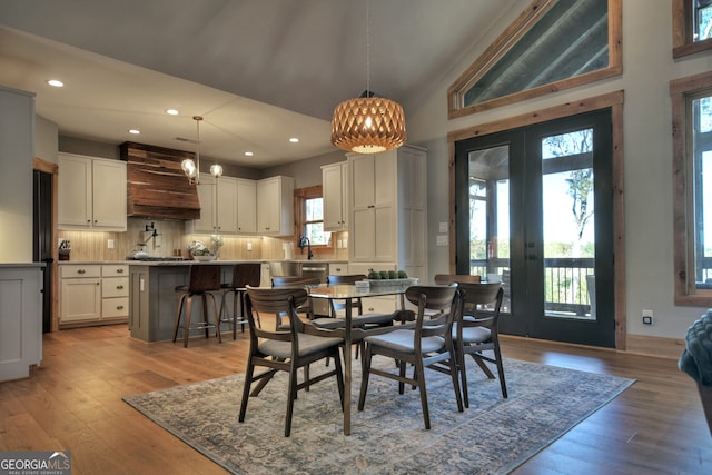 dining space featuring plenty of natural light, light hardwood / wood-style floors, sink, and french doors