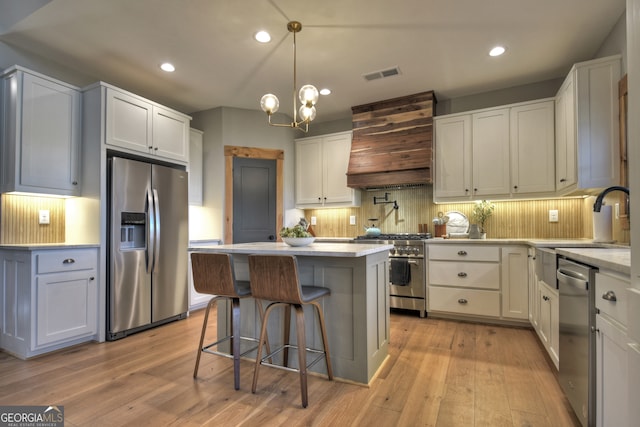 kitchen with stainless steel appliances, white cabinetry, and premium range hood