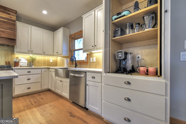 kitchen featuring tasteful backsplash, sink, light hardwood / wood-style flooring, dishwasher, and white cabinetry