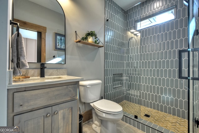 bathroom with tile patterned flooring, vanity, a shower with door, and toilet