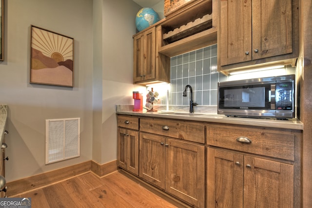 kitchen featuring tasteful backsplash, sink, and light wood-type flooring