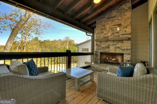 wooden terrace featuring an outdoor stone fireplace and ceiling fan