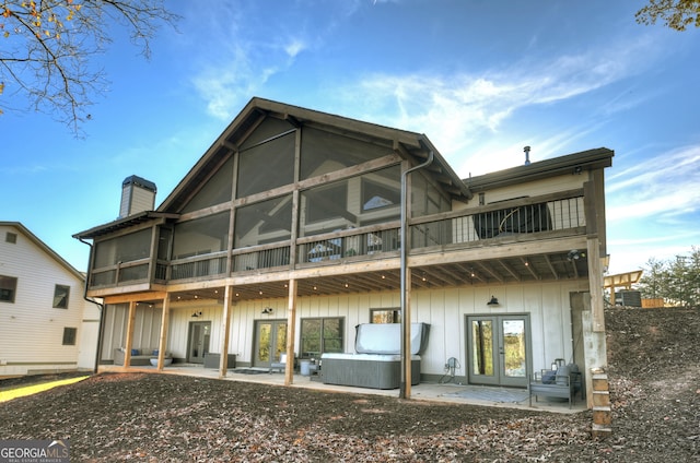 rear view of house with a sunroom, french doors, a hot tub, a balcony, and a patio