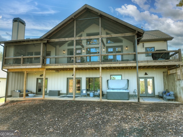 rear view of house with french doors, an outdoor hangout area, a balcony, a patio area, and a hot tub