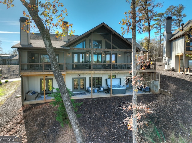 rear view of house with a jacuzzi, french doors, a patio, and a balcony