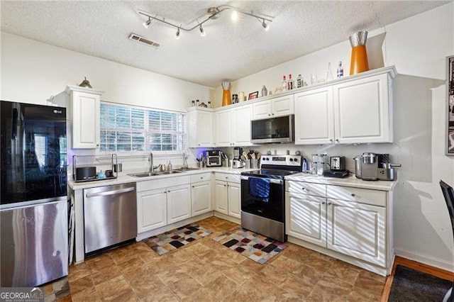 kitchen featuring a textured ceiling, sink, white cabinetry, and stainless steel appliances