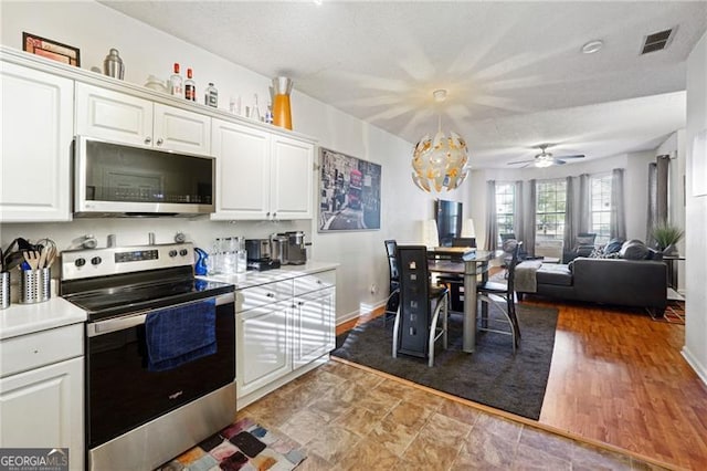 kitchen featuring white cabinetry, hardwood / wood-style floors, decorative light fixtures, ceiling fan with notable chandelier, and appliances with stainless steel finishes