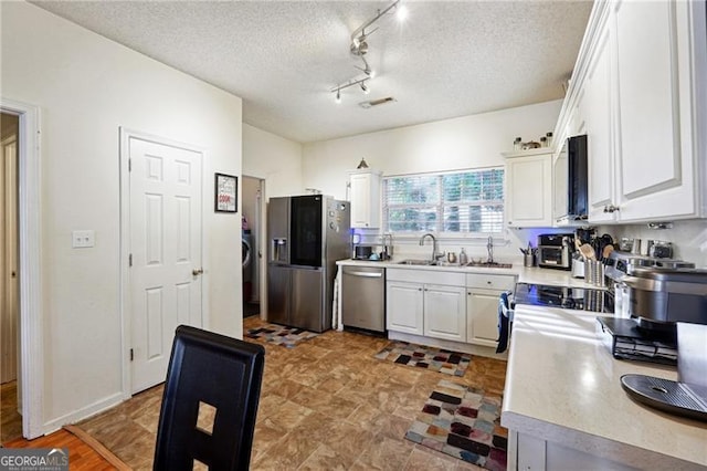 kitchen featuring white cabinetry, sink, stainless steel appliances, and a textured ceiling