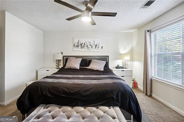 bedroom with ceiling fan, light colored carpet, and a textured ceiling