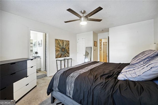 carpeted bedroom featuring ensuite bath, ceiling fan, and a textured ceiling