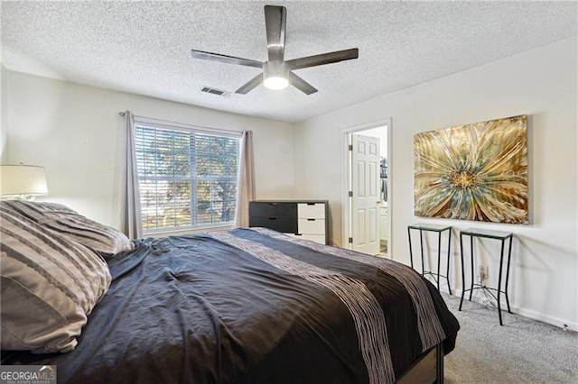 bedroom featuring a textured ceiling, light colored carpet, and ceiling fan