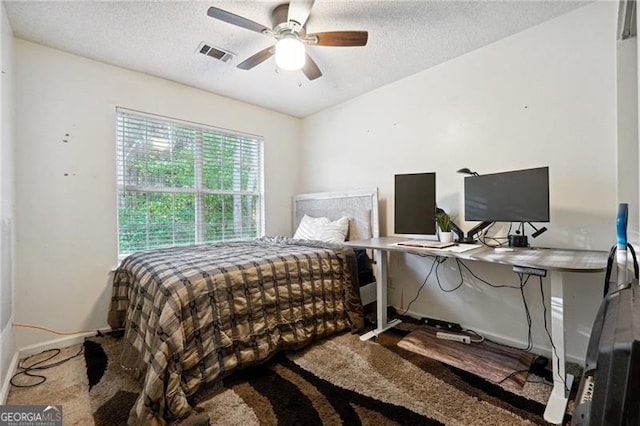 carpeted bedroom featuring ceiling fan and a textured ceiling