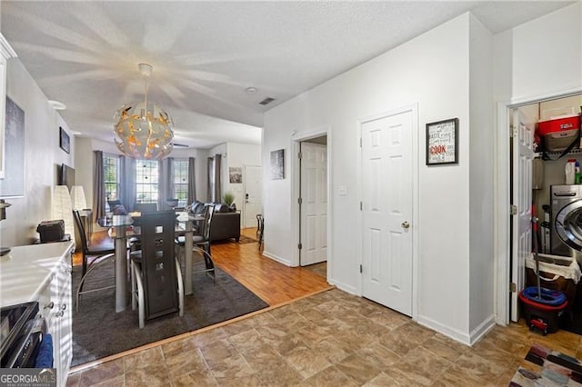 dining room with a chandelier, washer / dryer, and light wood-type flooring