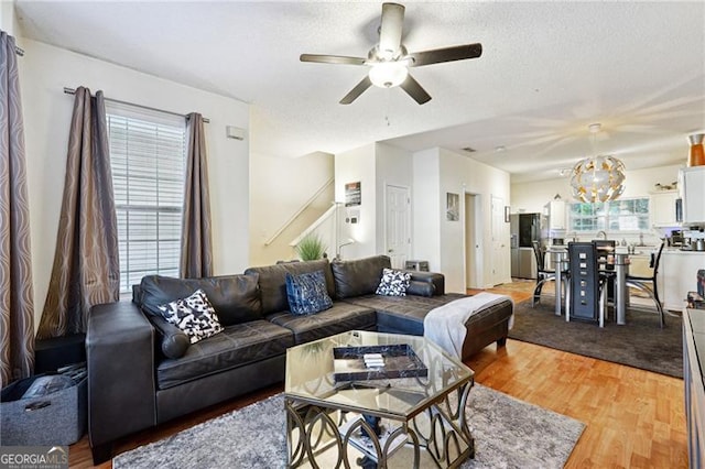 living room with a textured ceiling, ceiling fan with notable chandelier, and hardwood / wood-style flooring