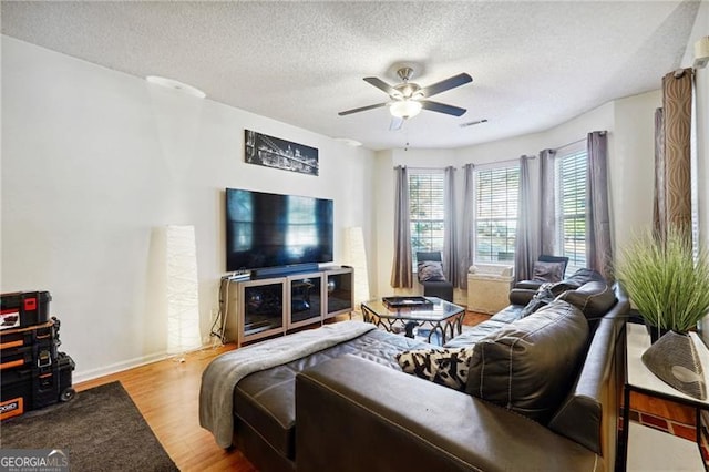 living room with ceiling fan, light hardwood / wood-style flooring, and a textured ceiling