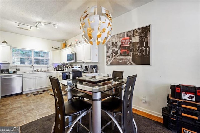 dining room with a textured ceiling, track lighting, and sink