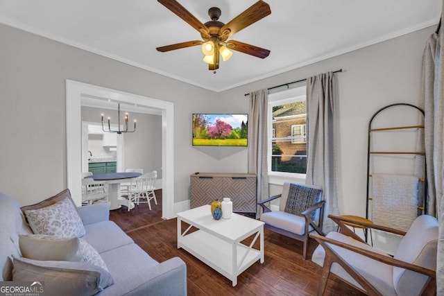 living room featuring dark hardwood / wood-style floors, crown molding, and ceiling fan with notable chandelier