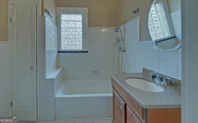 bathroom with tiled shower / bath, vanity, tile patterned flooring, and tile walls