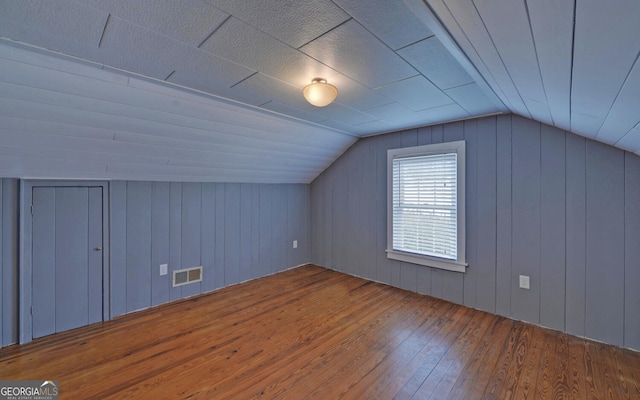 additional living space with hardwood / wood-style flooring and vaulted ceiling